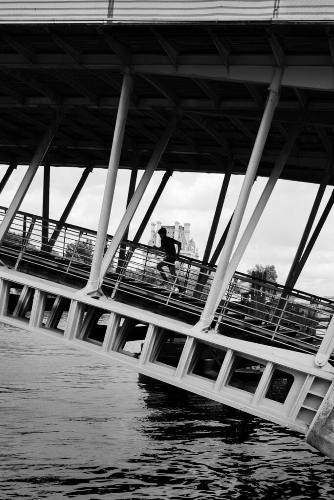 Young boy running on the bridge near the Louvre museum