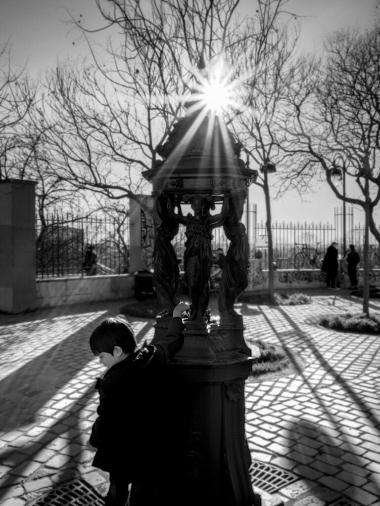 Young boy playing at the fountain in Belleville, Paris