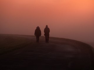 Two persons walking in the mist near the Lac du Der, Champagne, France.