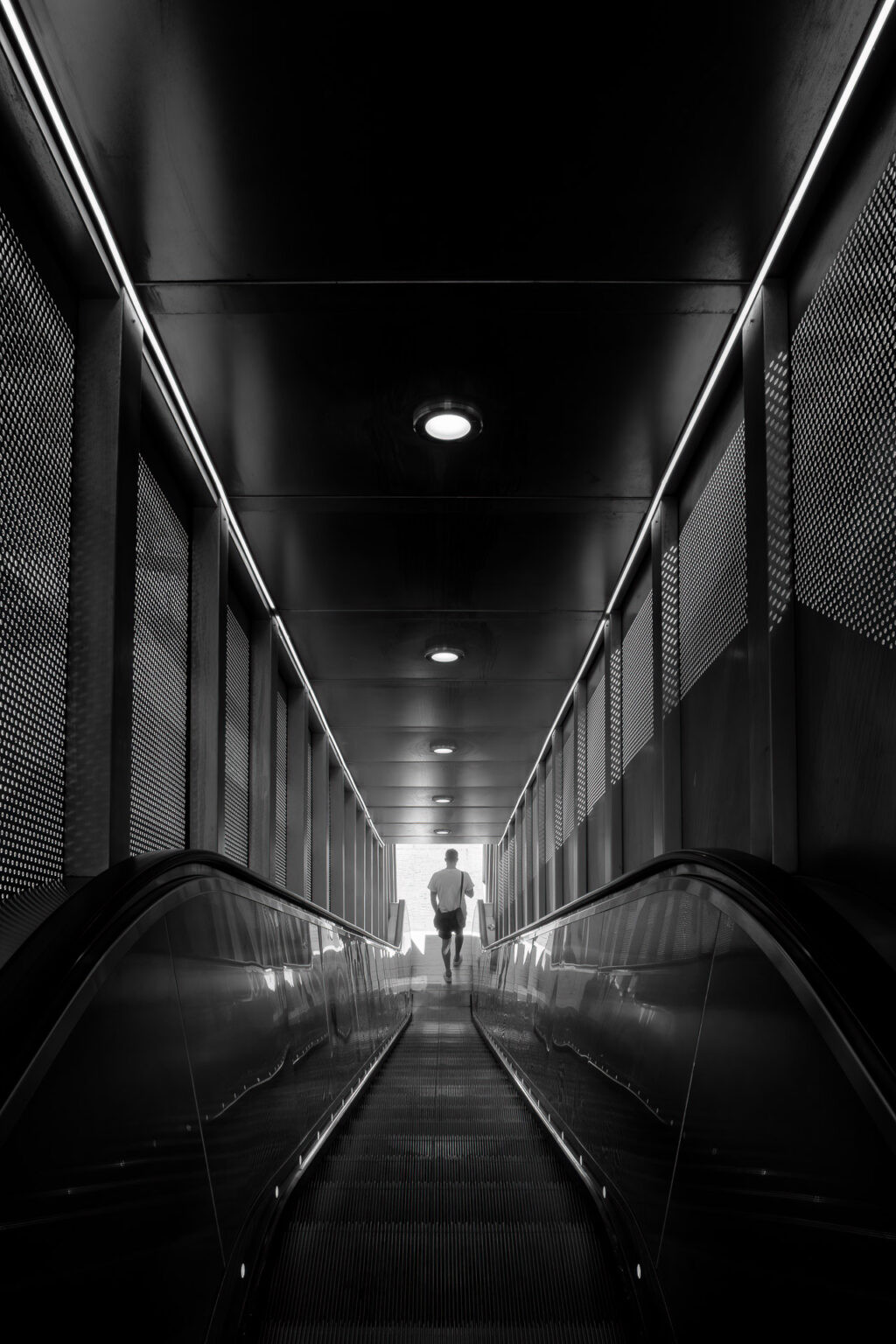 Homme descendant l’escalator à La Défense, Paris.