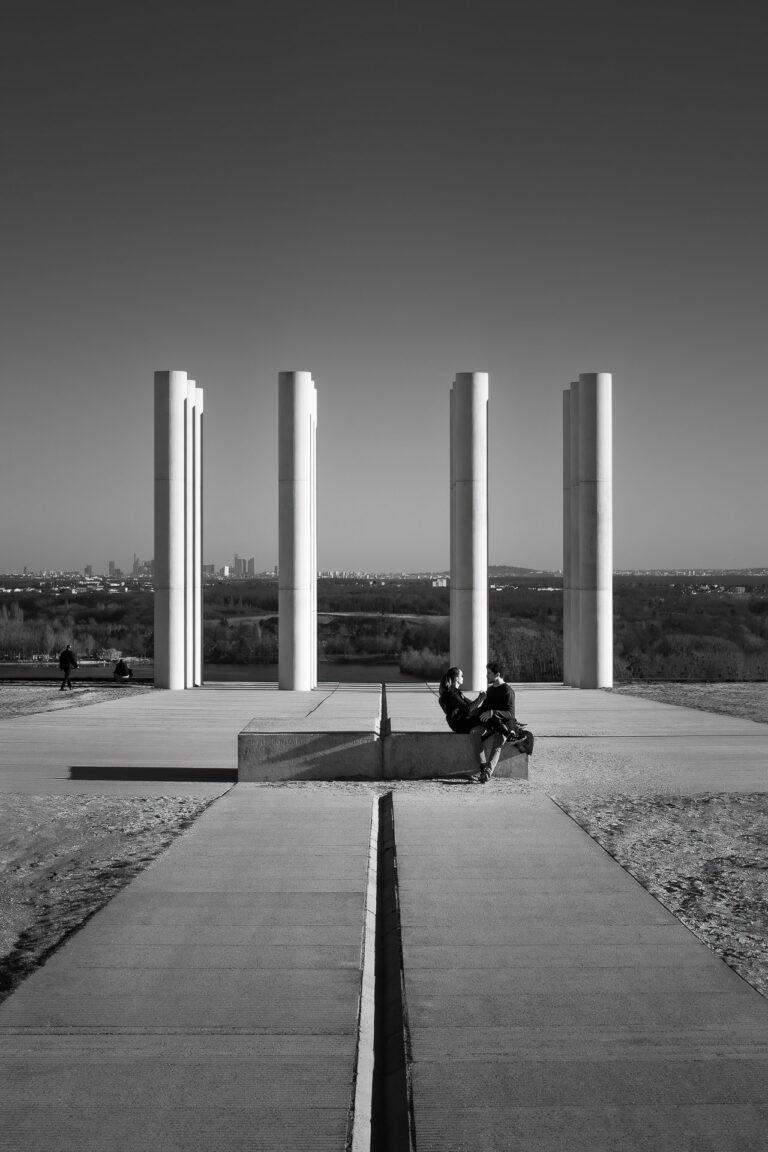 Paar vor den weißen Säulen der Esplanade der Axe Majeur, Cergy-Pontoise, Frankreich.