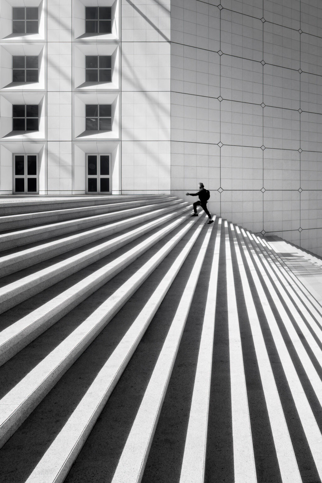 Man climbing the steps of the Grande Arche, La Défense, France.
