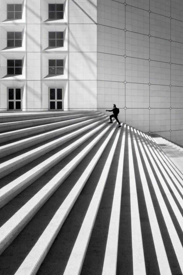 Hombre subiendo el escalón en el arco de La Defense, París