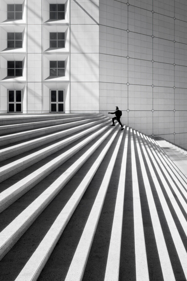 Man climbing the steps of the Grande Arche, La Défense, France.