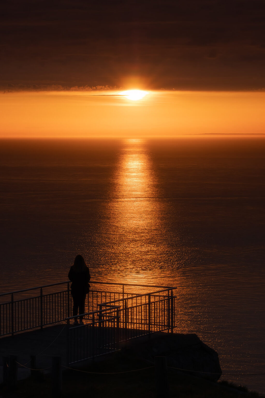 Femme regardant le coucher de soleil au cap Blanc-Nez, France.