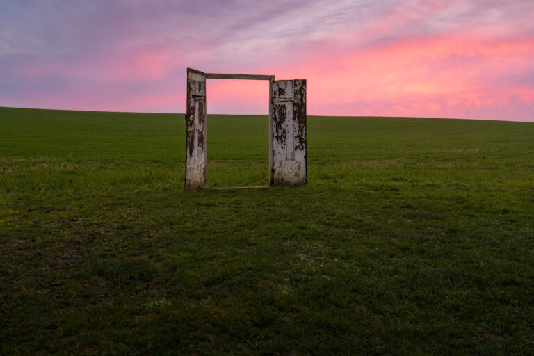 Weathered white door frame standing alone in a field at sunset, near Rennemoulin, France.